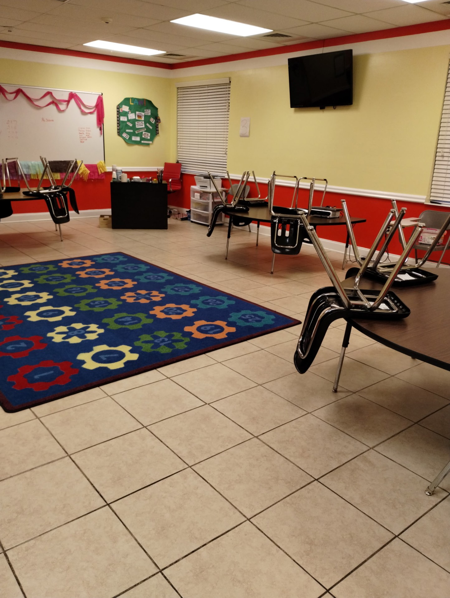 Freshly cleaned daycare classroom with colorful learning rug and chairs stacked on tables